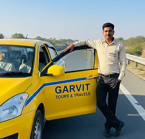 Garvit driver welcoming passengers beside a yellow taxi on the Jhunjhunu to Delhi highway